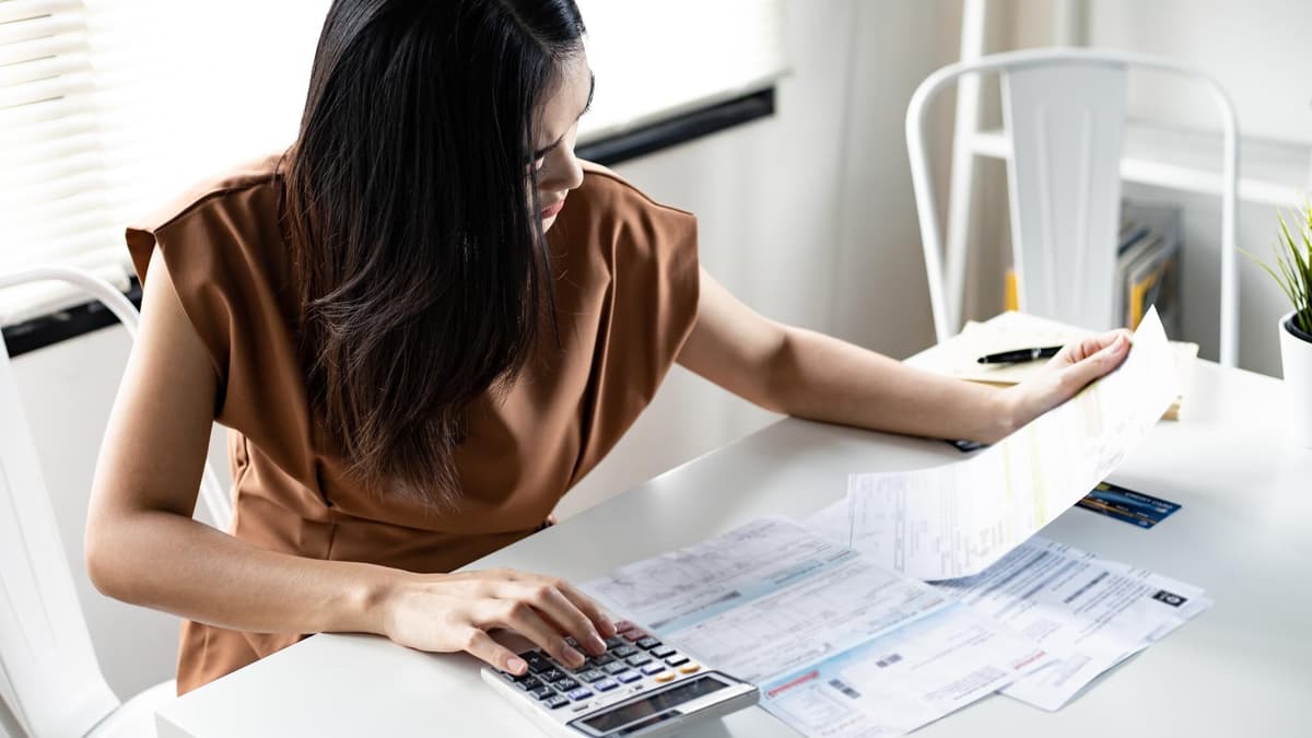 Woman at her desk adding up a pile of monthly invoices on a calculator