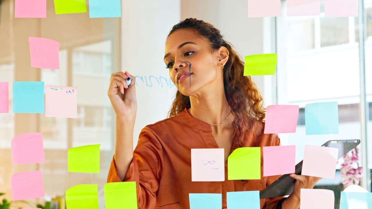 Business owner planning website pages with colorful sticky notes on a glass wall