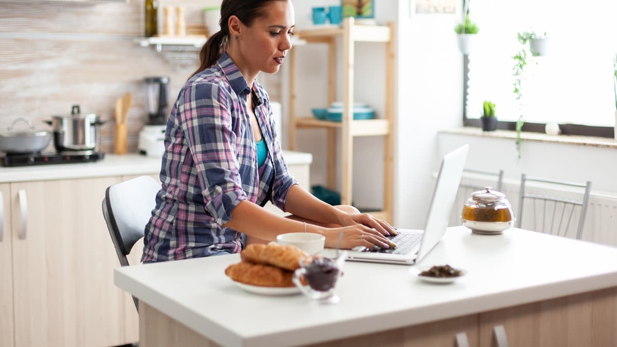 Agent working on a laptop in a bright kitchen between showings