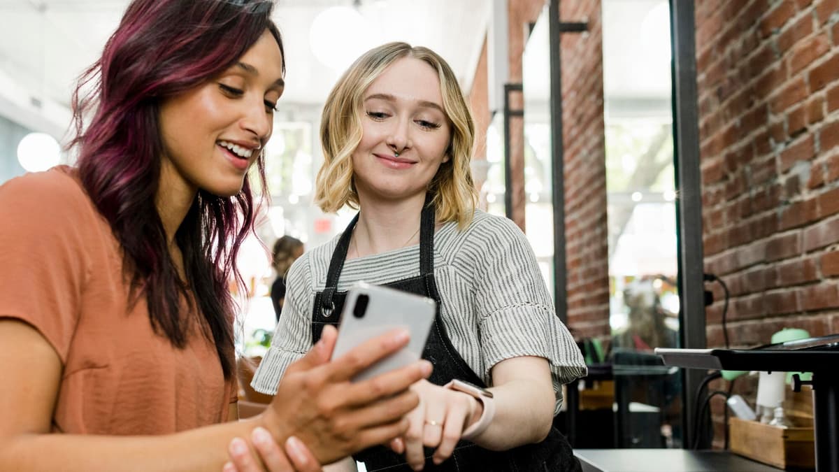 Salon customer showing her phone to the stylist after leaving a review