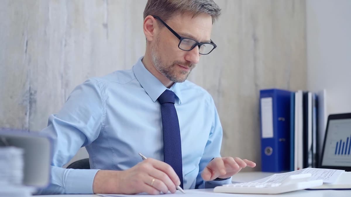 Man at his desk working out costs with a calculator and notepad