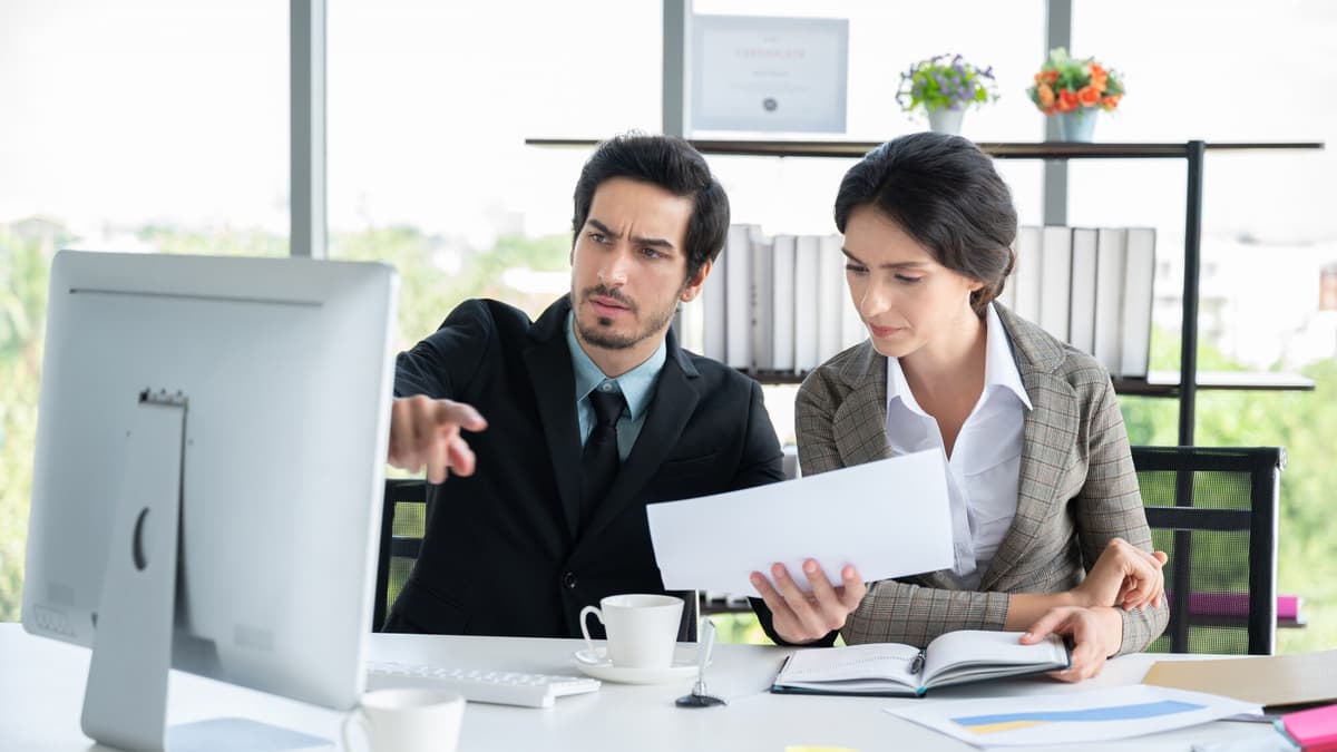 A lawyer and a consultant review a page together at a desk in a bright office
