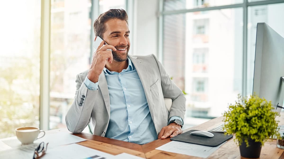 Smiling man in an office on a phone call