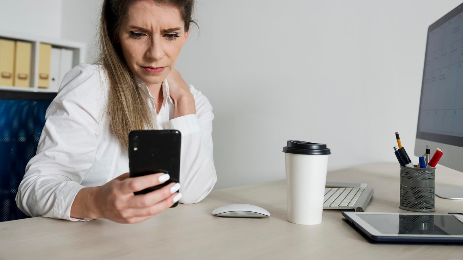 Business owner at her desk waiting for a slow website to load on her phone, ready to improve website speed