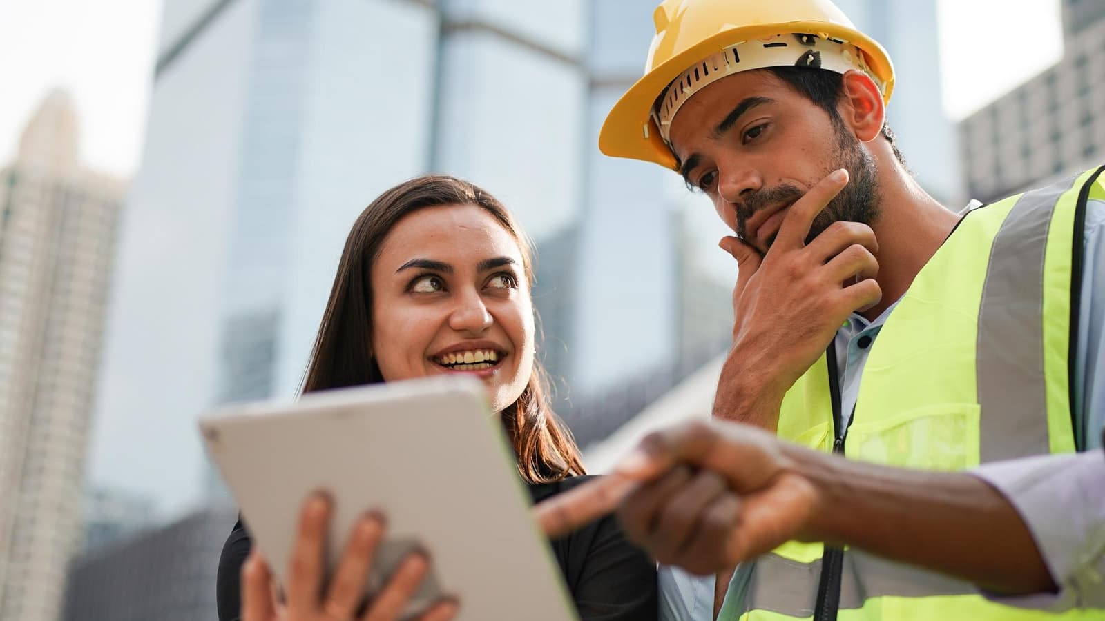 Contractor in a hard hat checking his company website on a tablet at a job site, an example of website design for construction company owners