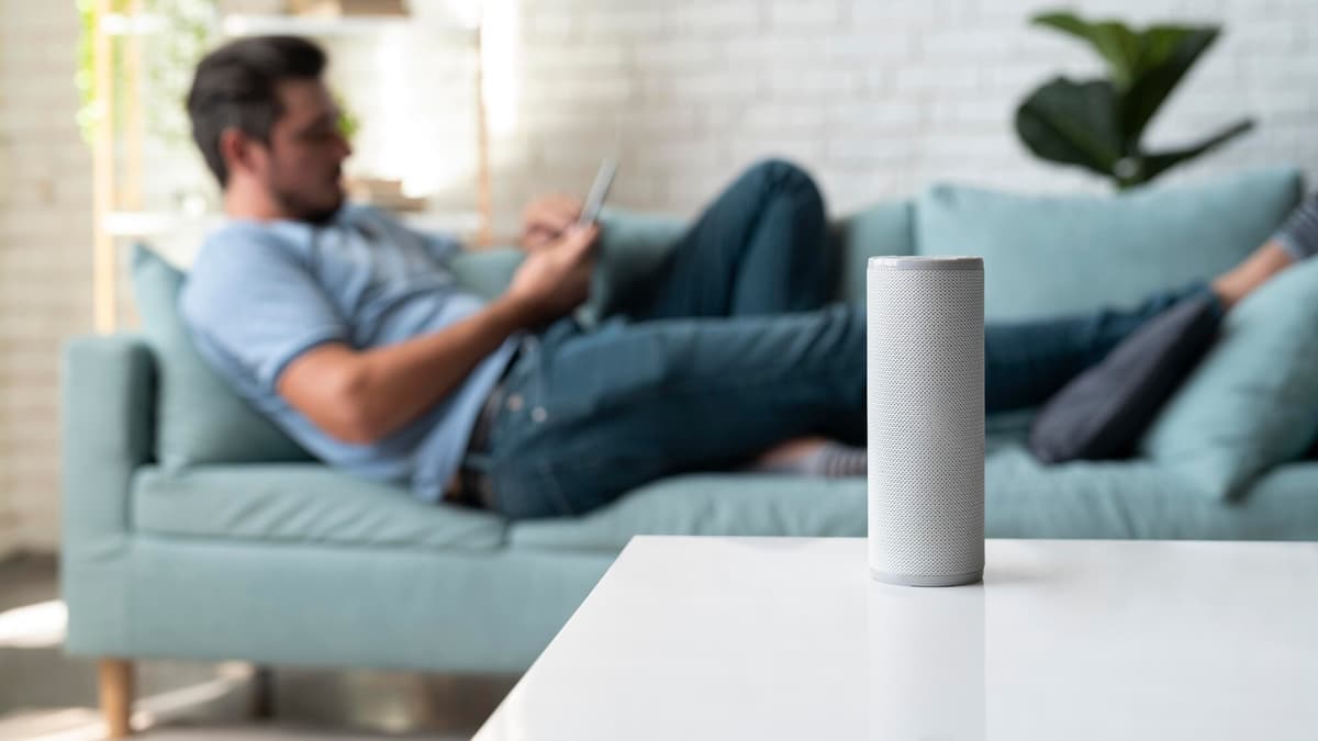 Man at home asking a smart speaker to compare local plumbers and request quotes