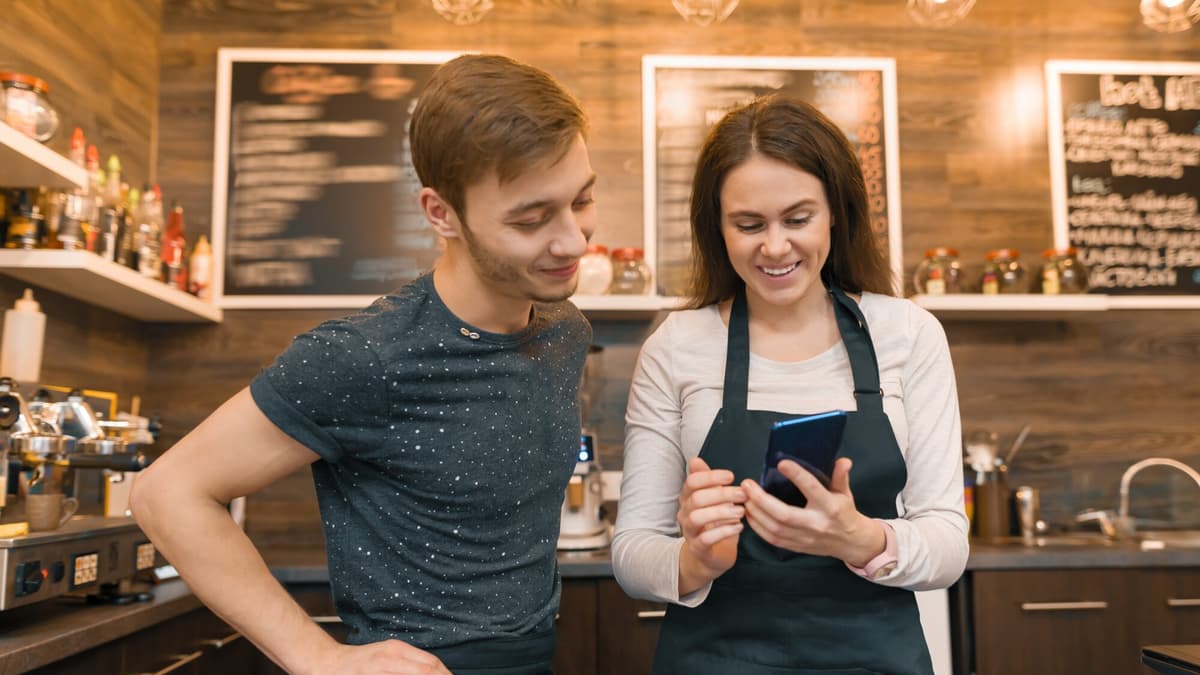 Restaurant owner checking her phone for missed customer calls behind the counter