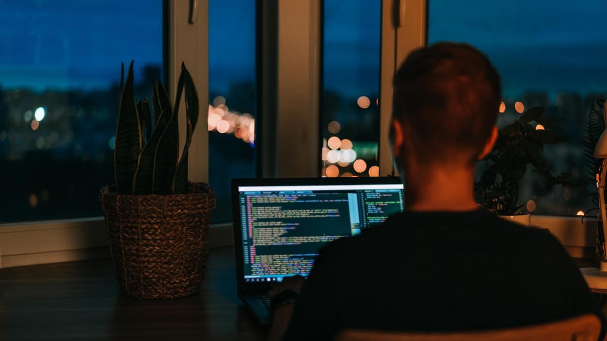 Developer running site tests on a laptop screen full of code in a dim office
