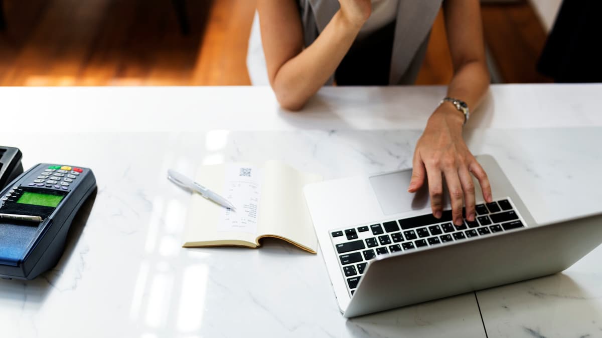 Small business owner working through a checklist on a laptop at a workshop counter