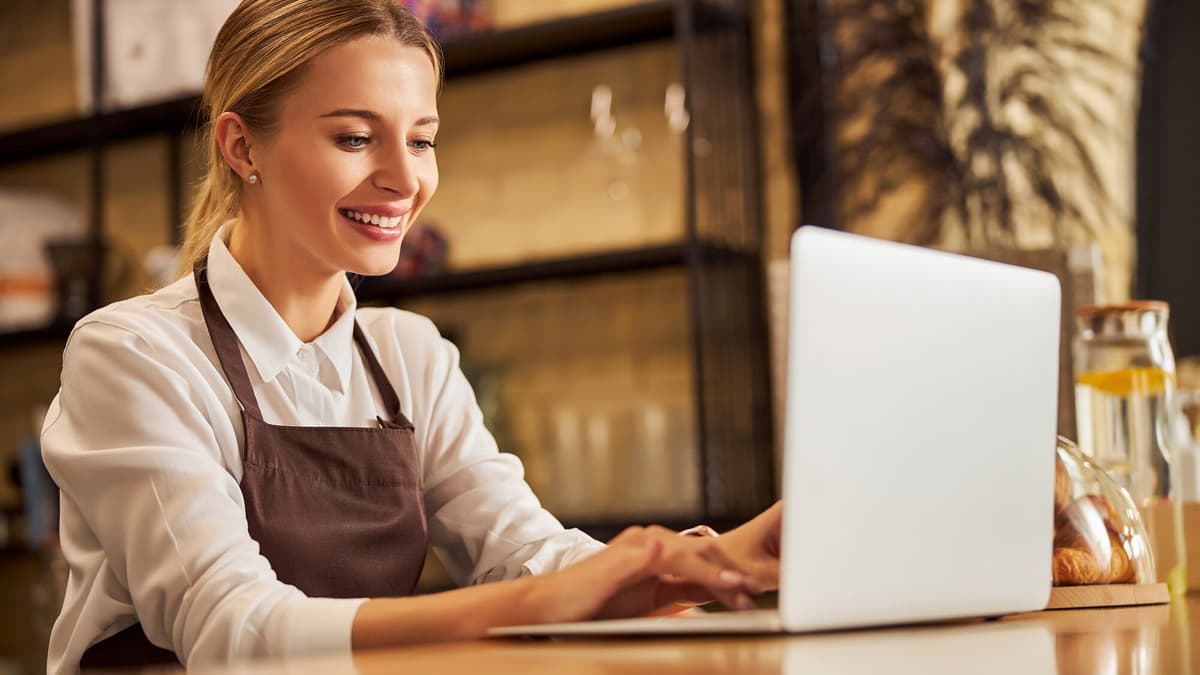 Local business owner checking her business listings on a laptop at the shop counter