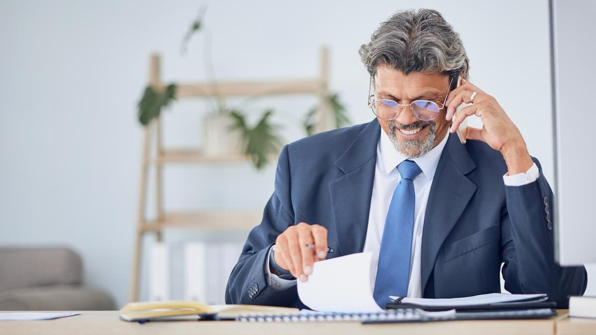 Lawyer reading printed documents at a desk with law books behind