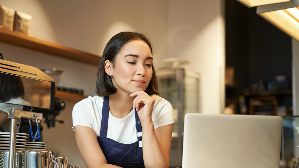 Business owner filling in her company details on a laptop at the counter