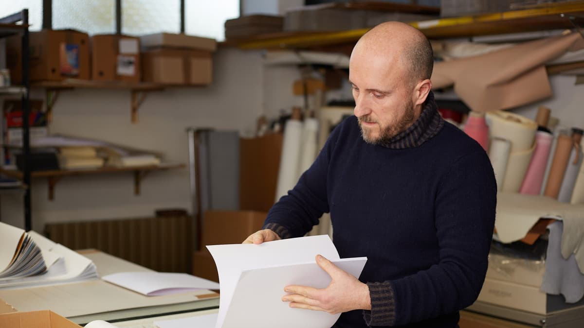 Contractor reviewing job paperwork and a laptop in a workshop office