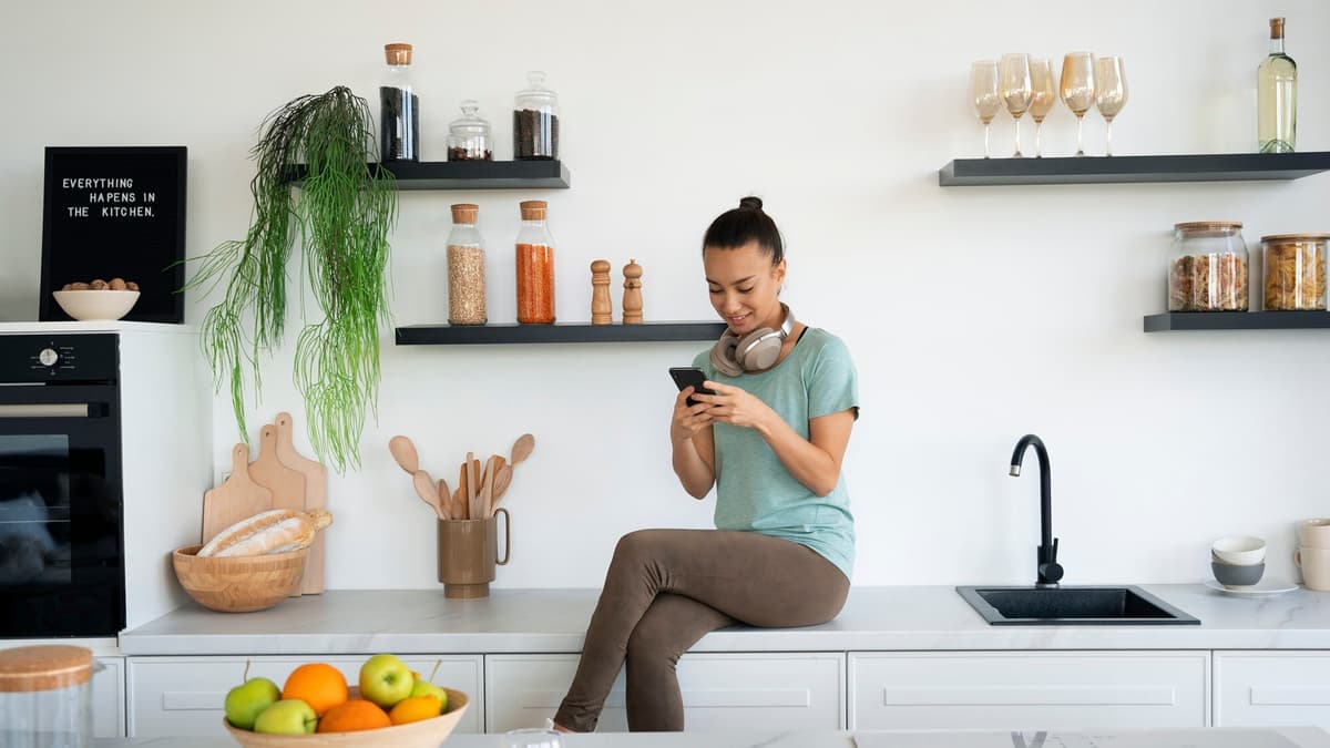 Homeowner at a kitchen counter filling out a contractor quote request on her phone