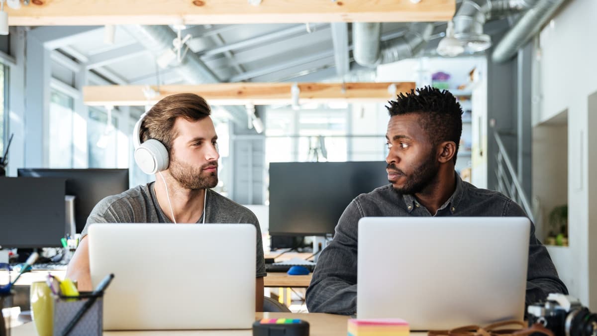Web developer and business owner at a laptop in a bright office deciding whether to fix or rebuild a slow website
