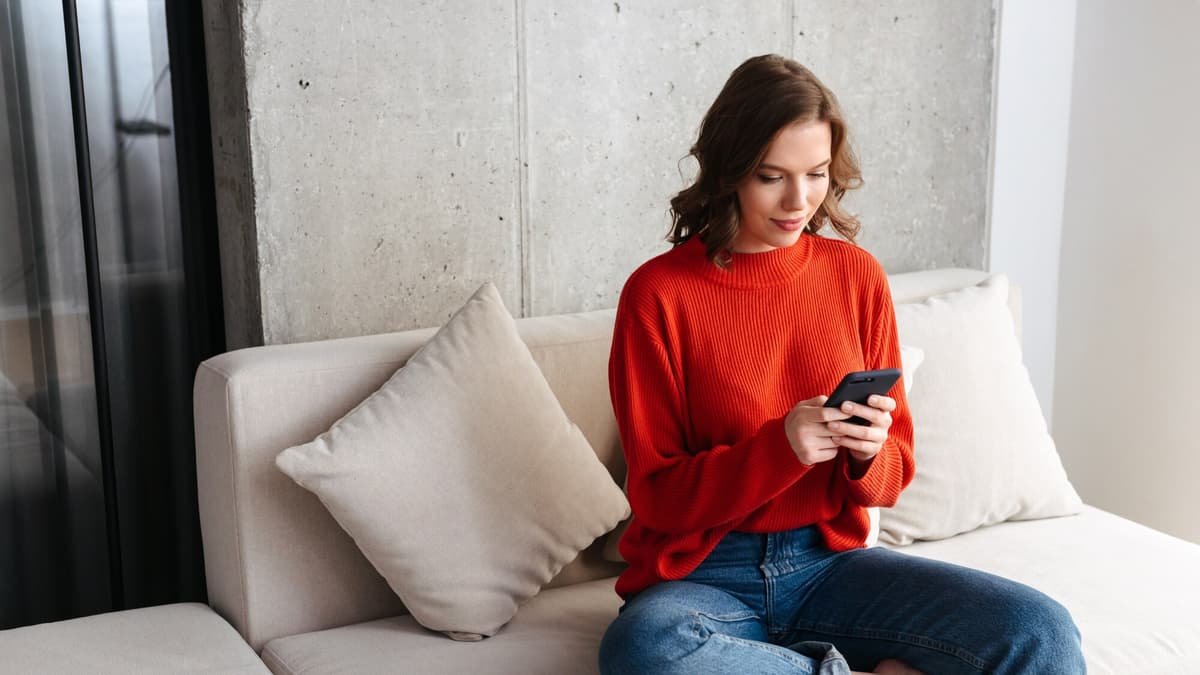 Person sitting on a sofa filling in a form on a smartphone at home