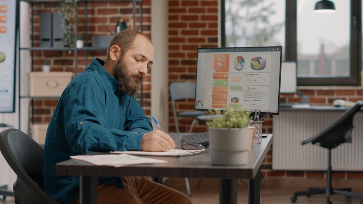 Marketer checking search results and a spreadsheet on a laptop to measure answer engine optimization