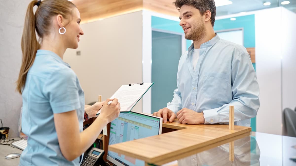 Dental office front desk where a receptionist checks in a patient who found the practice on Google