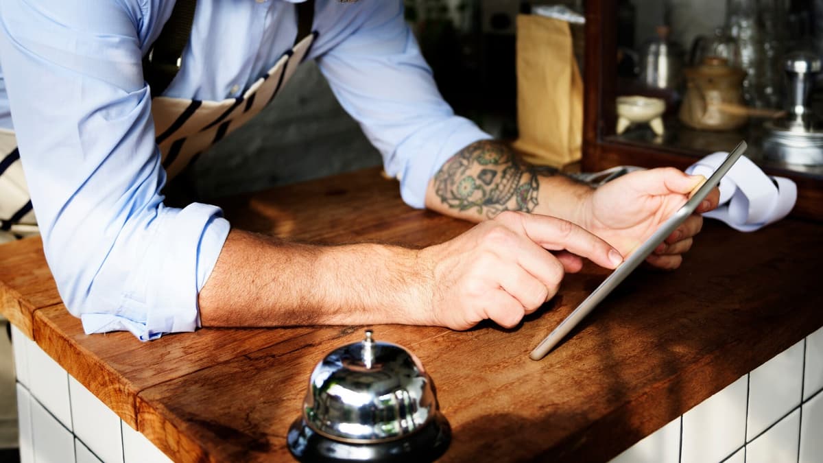 Bakery owner checking customer reviews on a tablet in his shop