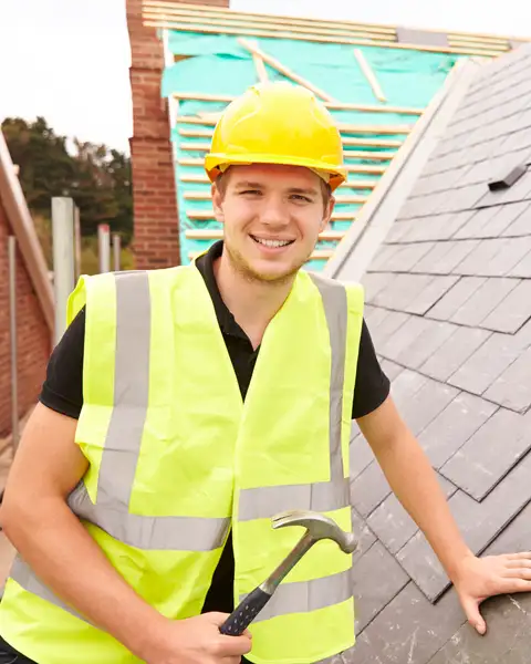 A roofer laying slate tiles smiles at the camera