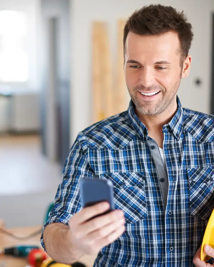 A contractor on a job smiles at a new lead on his phone